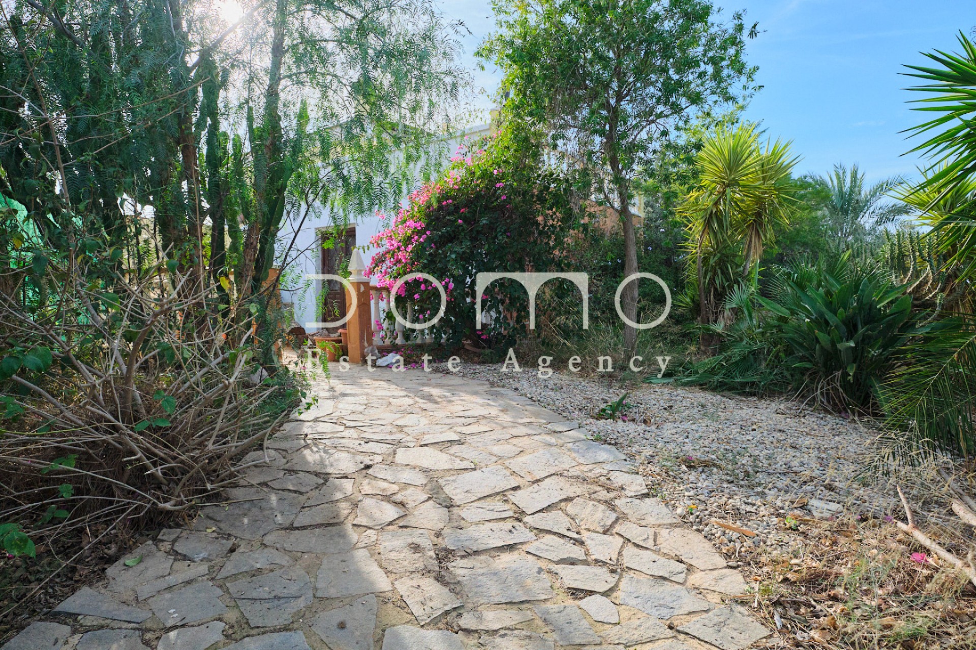 Allée de jardin avec végétation locale menant à l’entrée du cortijo.