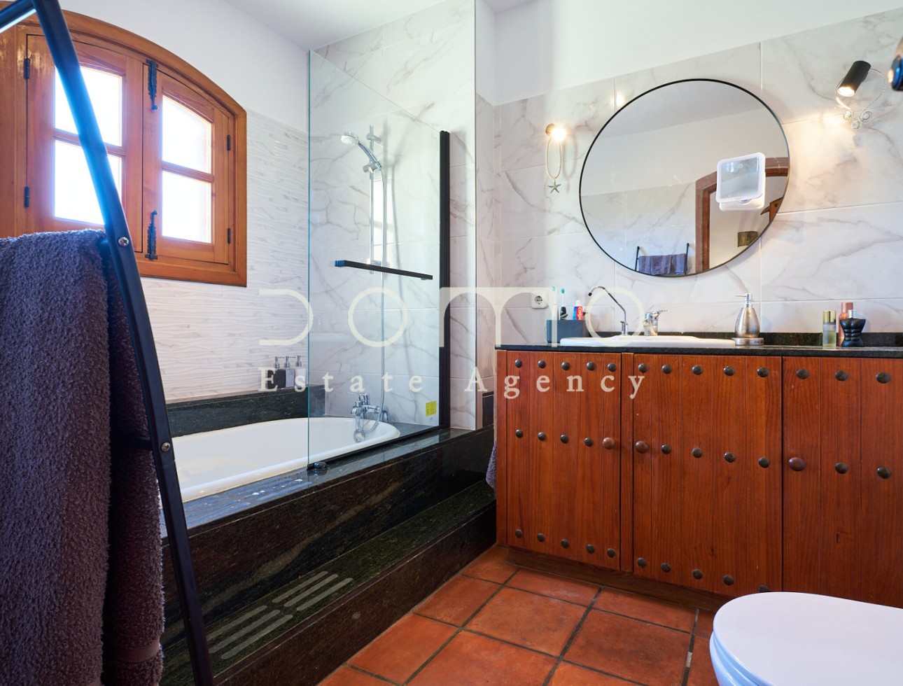 Baño renovado con bañera, mampara de cristal y mueble de madera maciza.