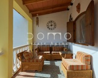 Covered porch of the country house with seating area and rustic furniture, perfect for outdoor relaxation.