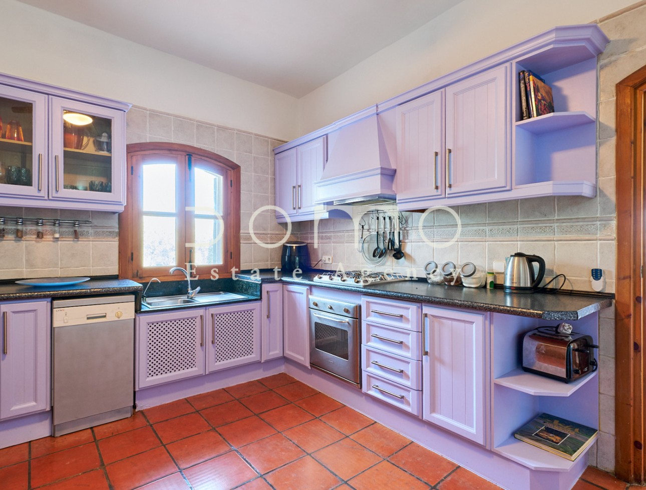 Cuisine entièrement équipée de style rustique avec meubles couleur lavande et électroménagers intégrés.