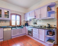 Cuisine entièrement équipée de style rustique avec meubles couleur lavande et électroménagers intégrés.