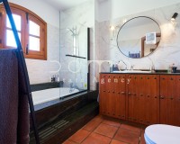 Renoviertes Badezimmer mit Badewanne, Glaswand und Waschtisch aus Massivholz.