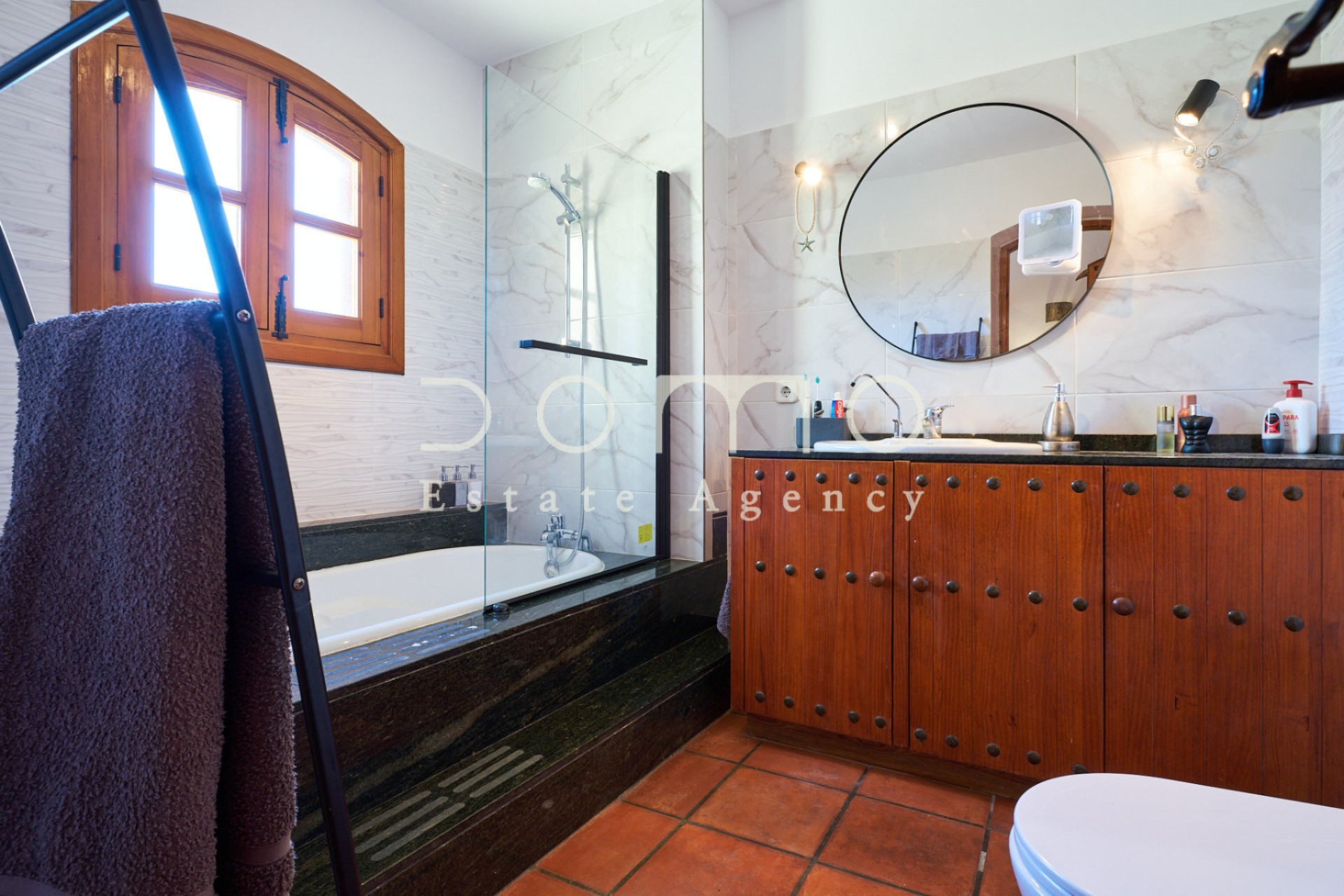 Renoviertes Badezimmer mit Badewanne, Glaswand und Waschtisch aus Massivholz.