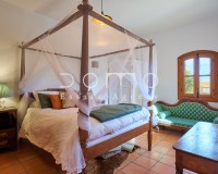 Spacious master bedroom with four-poster bed and rustic décor, filled with natural light.