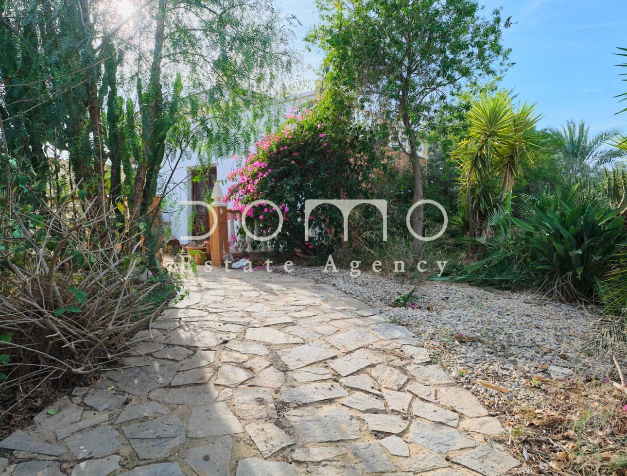 Tuinpad met inheemse beplanting dat naar de ingang van de cortijo leidt.