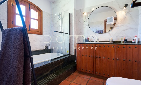 Renoviertes Badezimmer mit Badewanne, Glaswand und Waschtisch aus Massivholz.