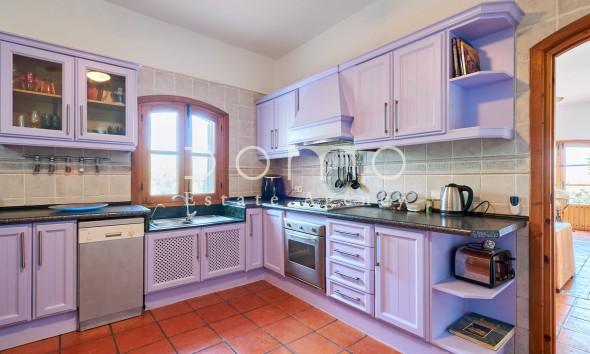 Voll ausgestattete Landhausküche mit lavendelfarbenen Schränken und integrierten Geräten.