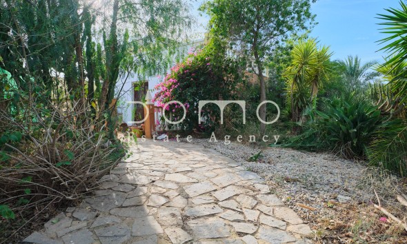 Gartenweg mit einheimischer Bepflanzung, der zum Eingang des Cortijos führt.